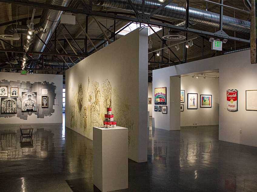 An art gallery with various artworks on display, including murals, portraits, and a Campbell's soup can artwork labeled 