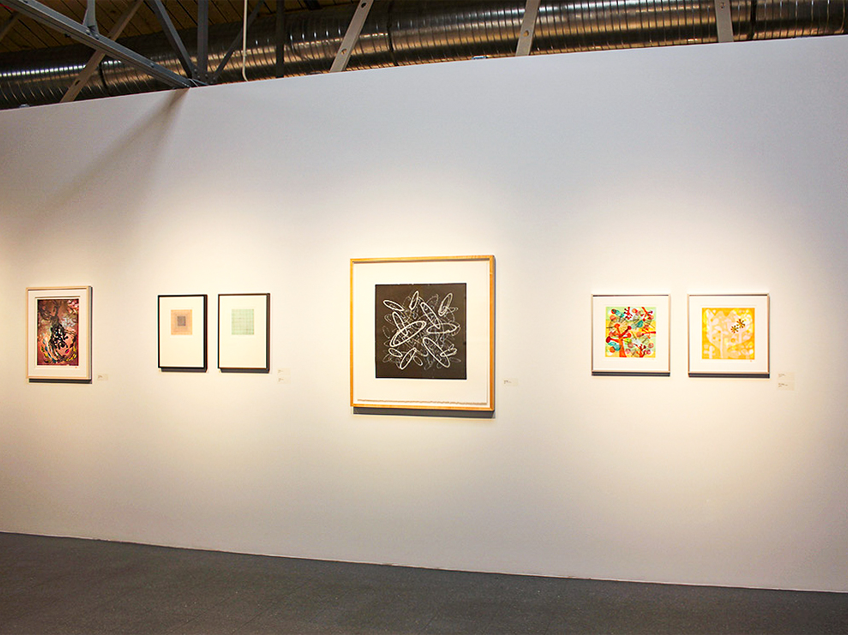 An art gallery wall displaying six framed artworks under spotlights.