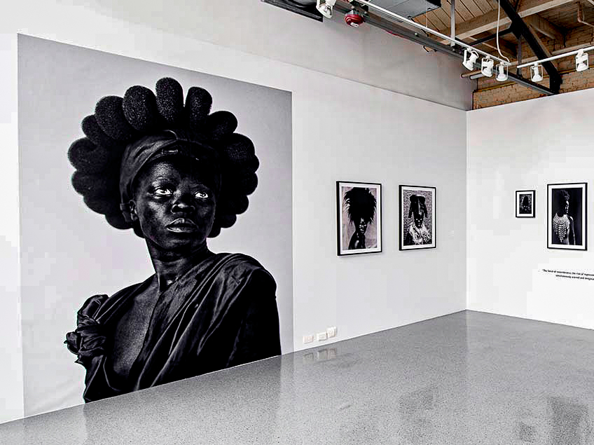Art gallery with a large black-and-white portrait and three smaller framed portraits on display.