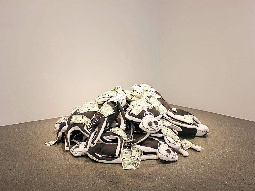 A pile of black and white plush cartoon-like figures covered with faux dollar bills in an art gallery.