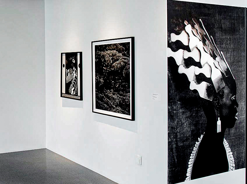 Art gallery displaying three black-and-white framed artworks on white walls.
