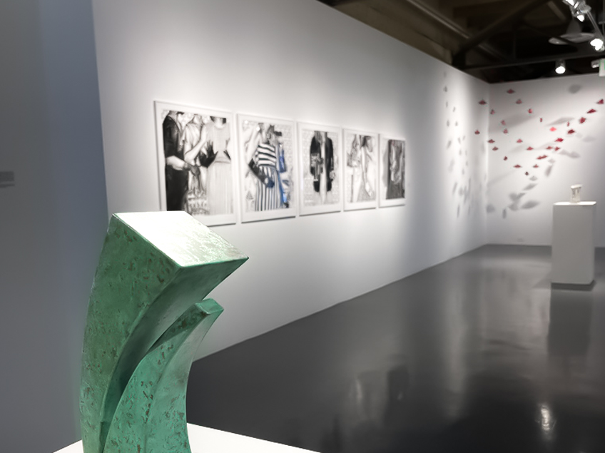 Contemporary art gallery with a green abstract sculpture and photographs on display.