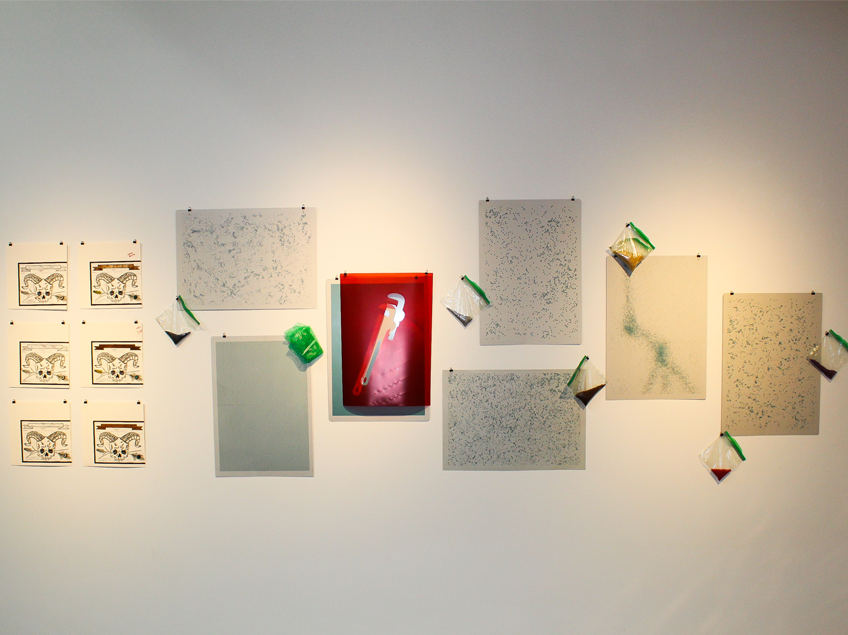Wall with abstract artworks and a red image of a wrench, accented by small plastic bags.