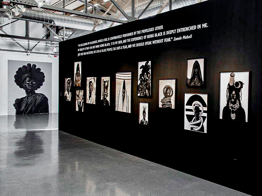 Art gallery with black-and-white portraits and a large wall quote.