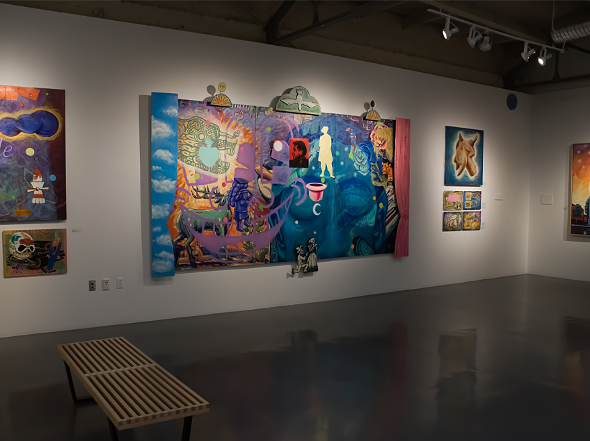 Art gallery wall with colorful abstract and surreal paintings, featuring a large central piece and several smaller artworks.