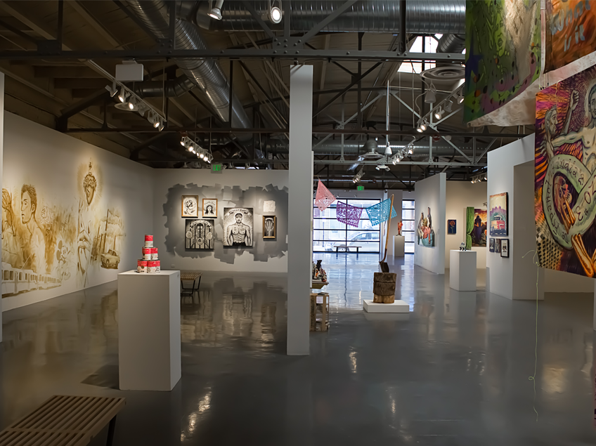 A modern art gallery with paintings, sculptures, and colorful hanging fabrics.