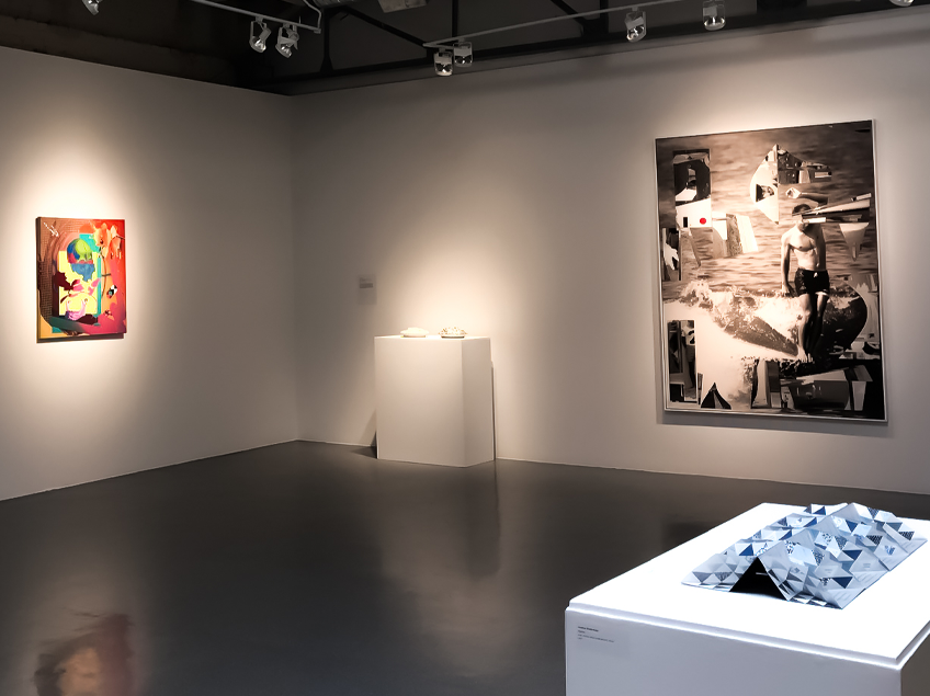 Gallery with abstract painting, black and white photo, and geometric sculpture under spotlights.