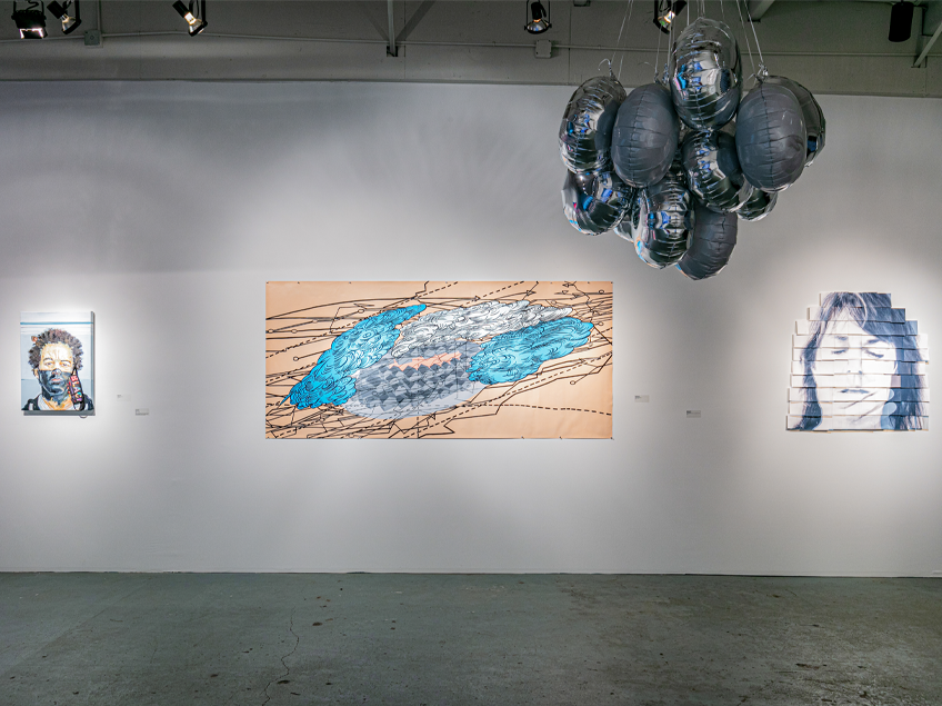 Gallery view, starting with a face portrait wearing a mask, followed by an abstract painting in blues and tans with line work, and another face painting. A Mylar balloon installation hangs from the wall.