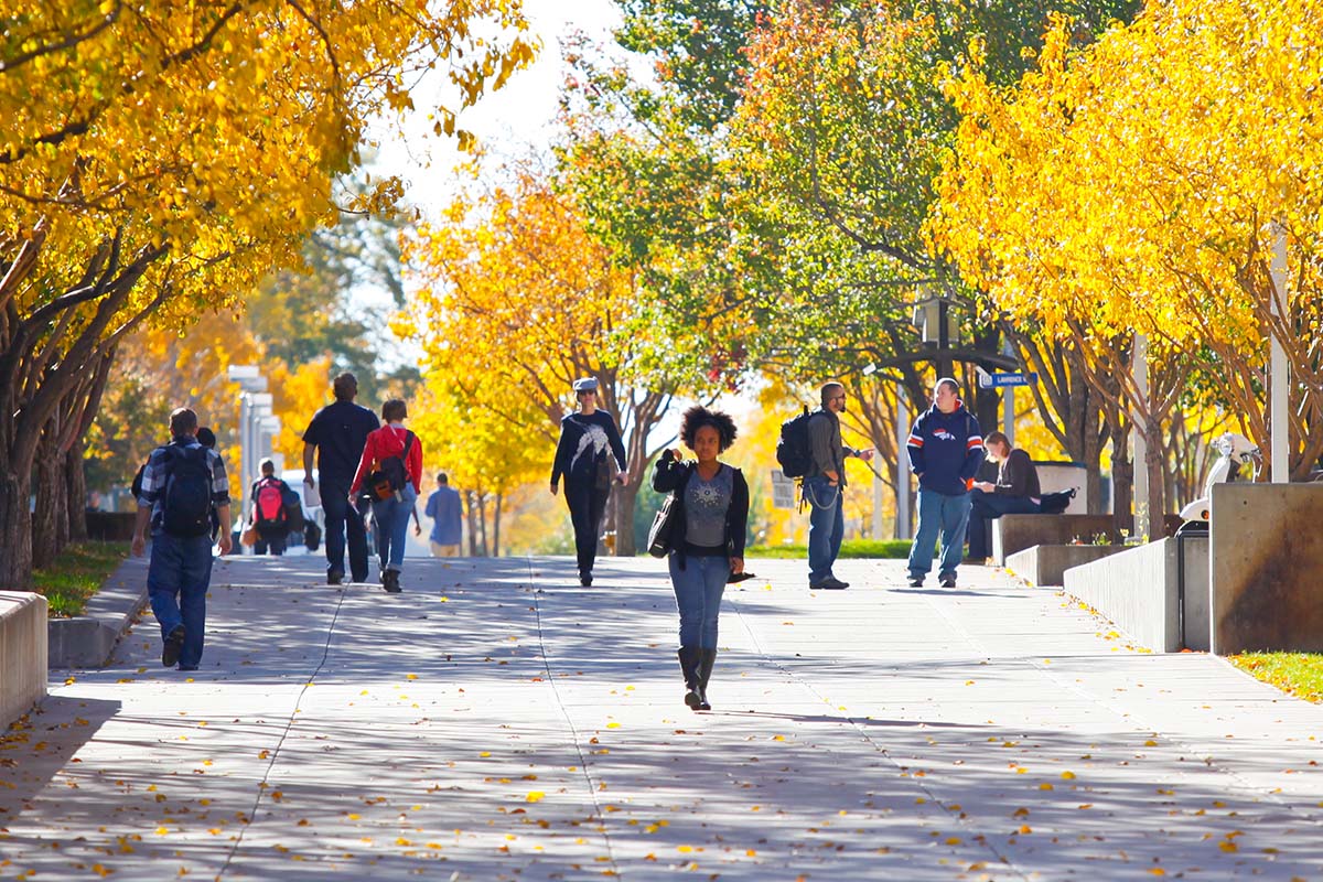 Students walking through Auraria Campus on a leafy fall day.
