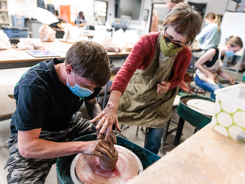 Professor Tsehai Johnson assists a student with their pottery-throwing exercise.