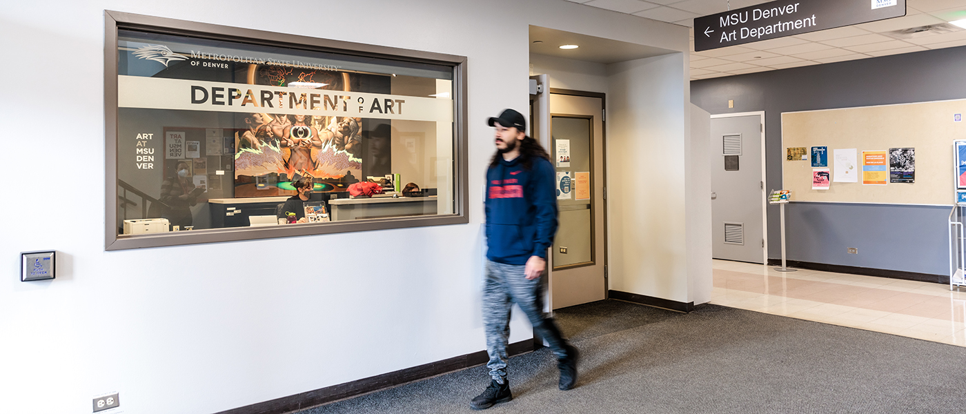 A student strolls past the outside of the main office of MSU Denver Art.