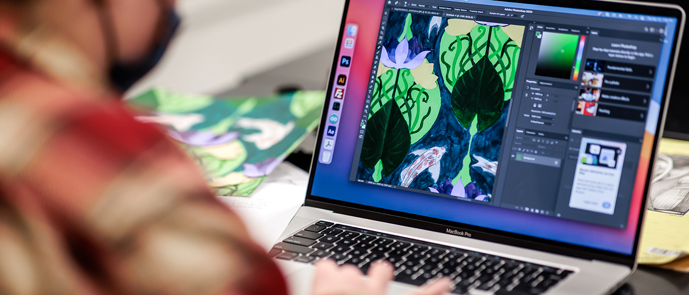 A person works on a graphic design program on a laptop