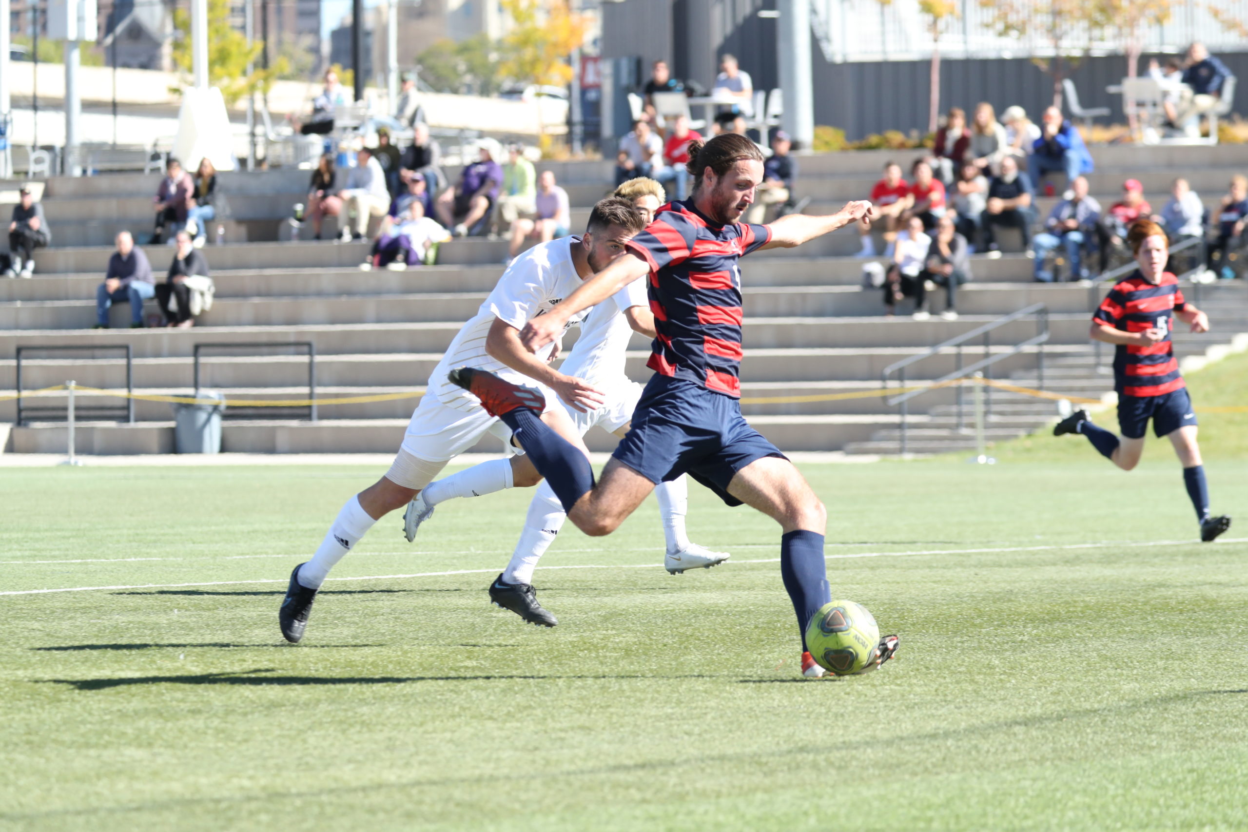 Men's soccer player Aidan Bates sets up for a shot during a game in 2021 with the Roadrunners crowd in the background.