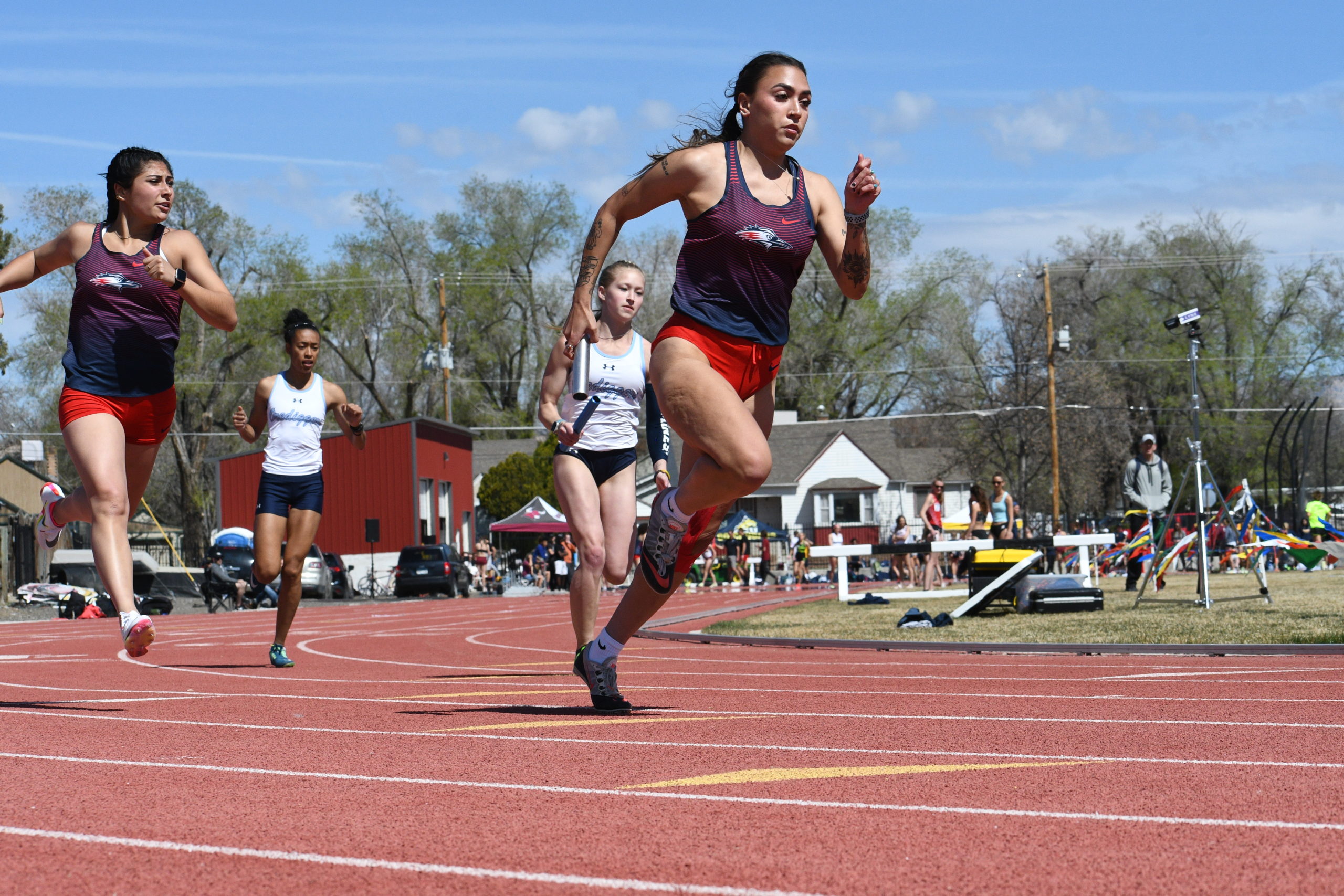 Women's track athlete Allyssa Romero leads during a relay race after receiving a handoff.