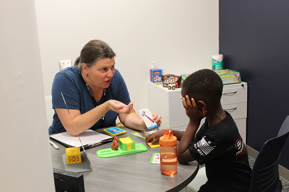 Graduate MS SLP student (left) working with elementary school aged child (right)