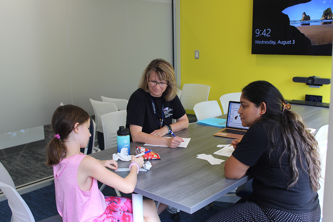 Graduate MS SLP student (right) and Clinical Educator (left) working with elementary school aged child (center)