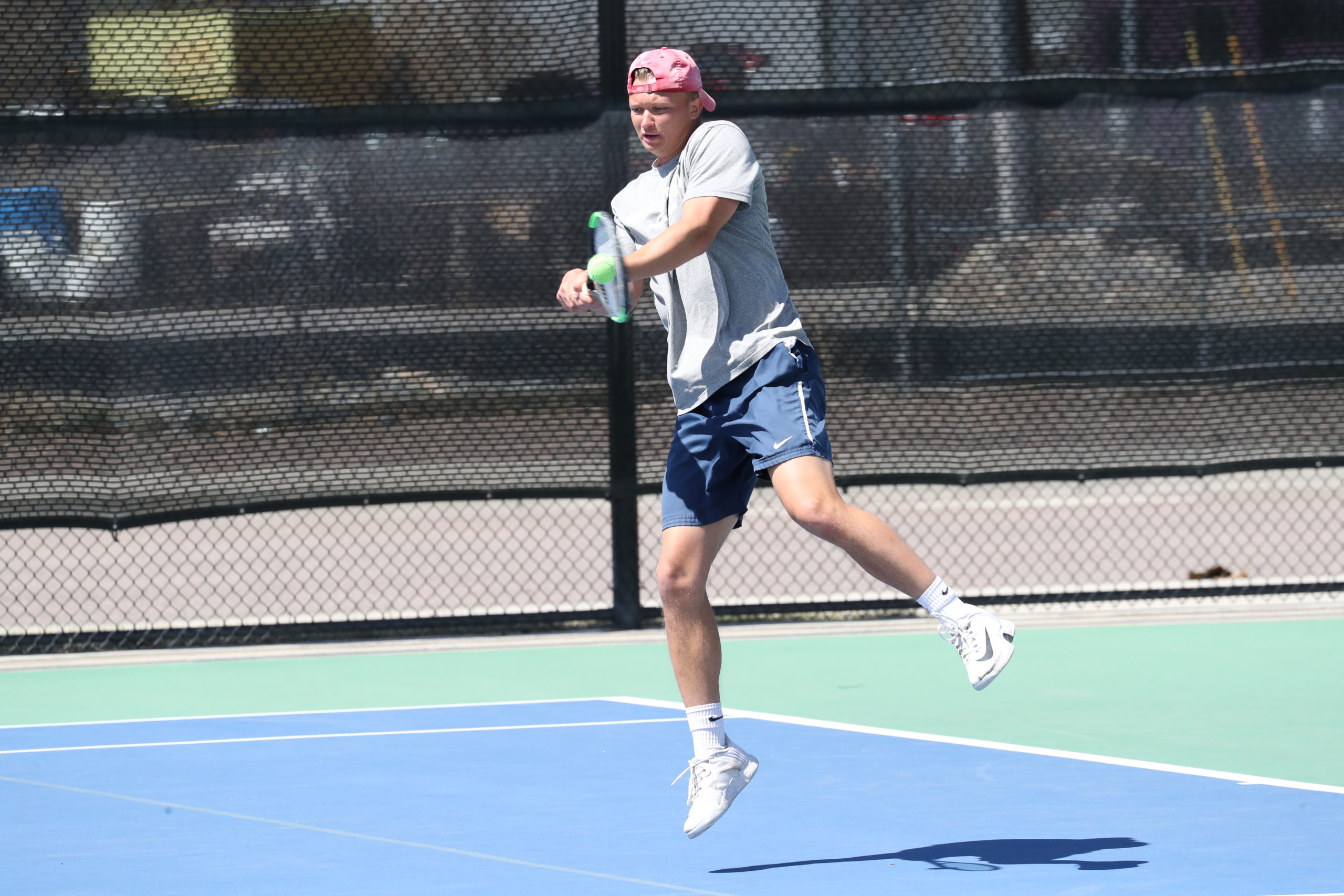 Men's tennis player David Kijak makes contact on a back-handed shot during a match in 2022.