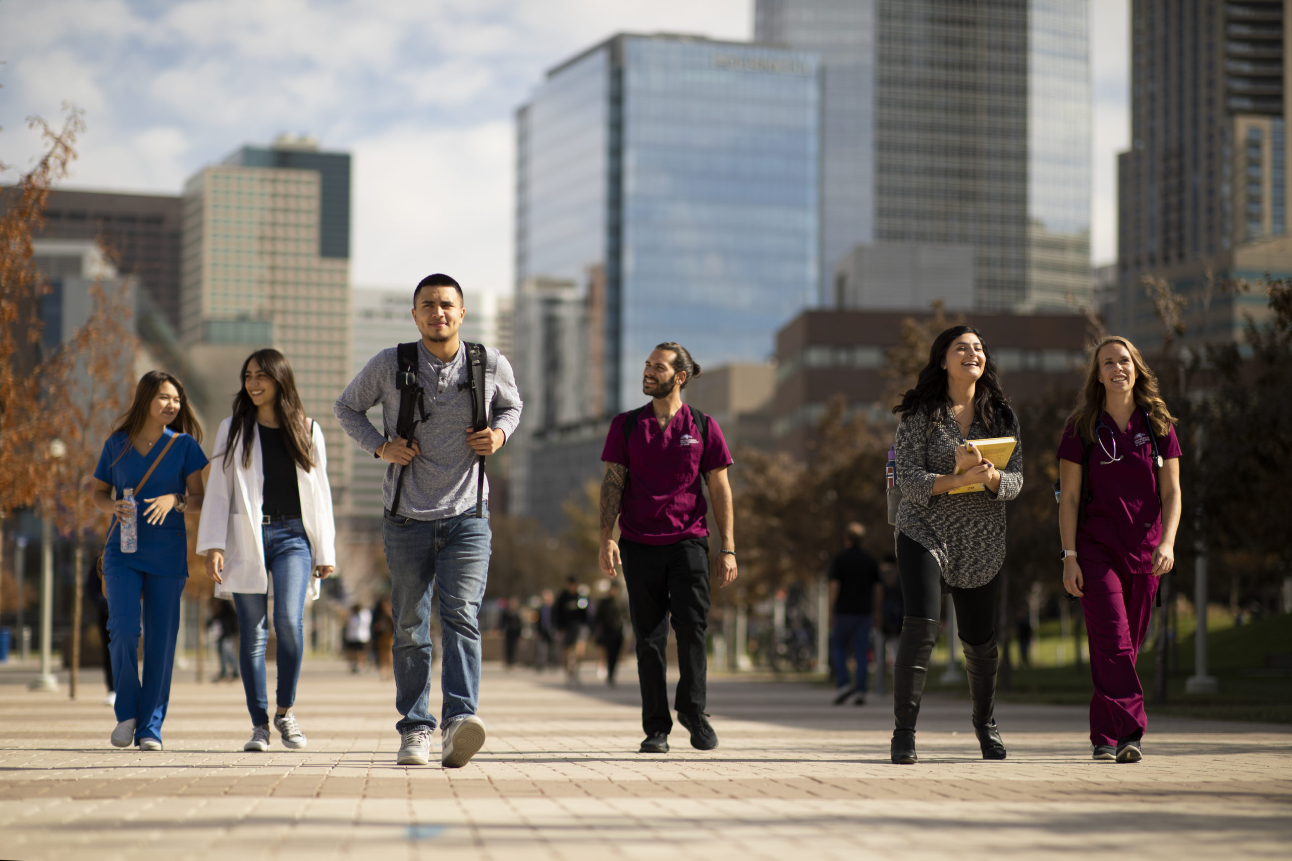 Group of students walking through campus with downtown Denver in the background.