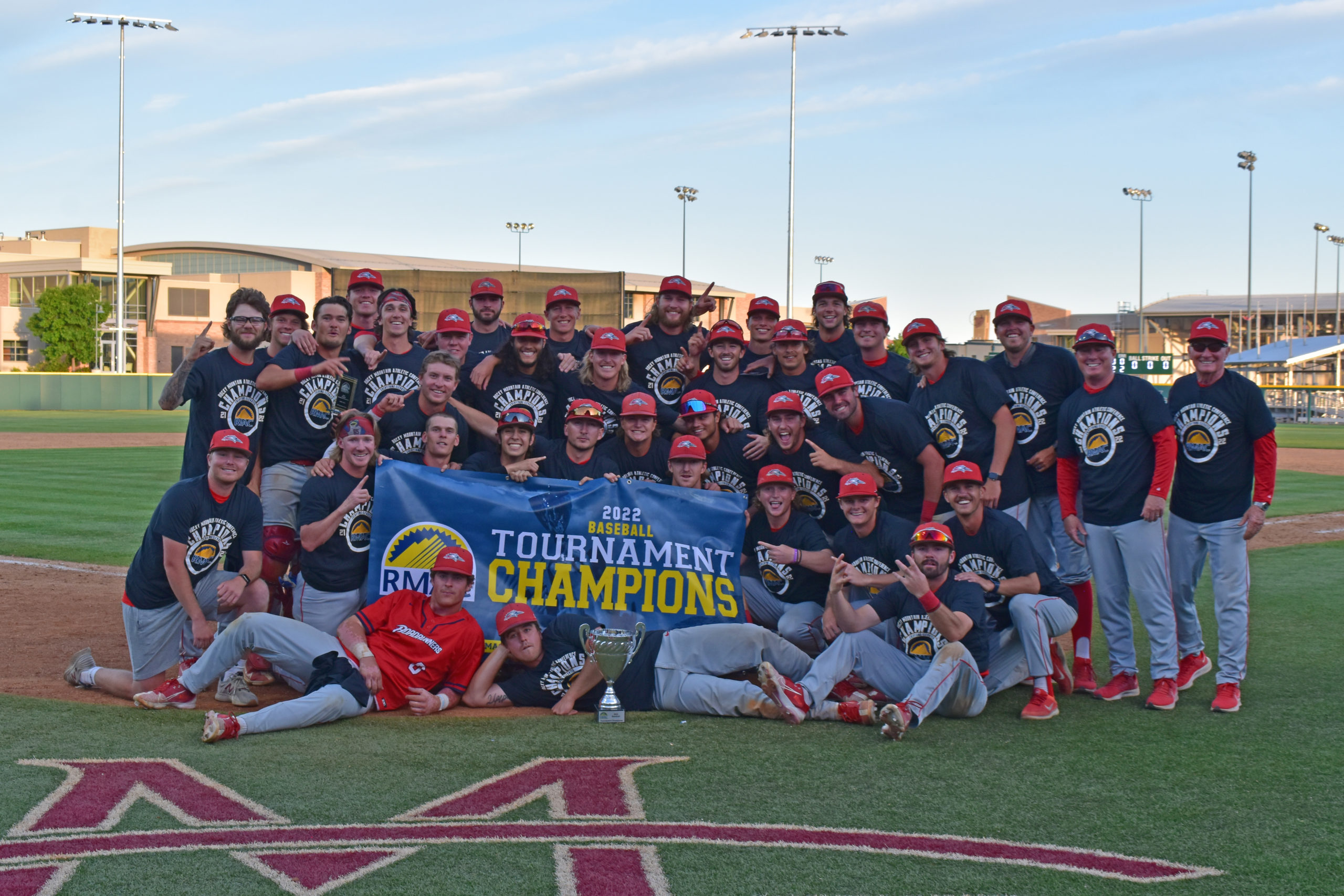 Roadrunners baseball team with the RMAC Championship banner after the conference title game in 2022.