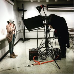 Students using specialized photography equipment. Interestingly, the subject of the photo they are taking is wearing an old fashioned gasmask.