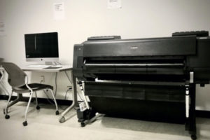 One of our large format Canon printers, shown next to an unoccupied iMac workstations.