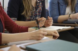 Close up of students hands on desks.