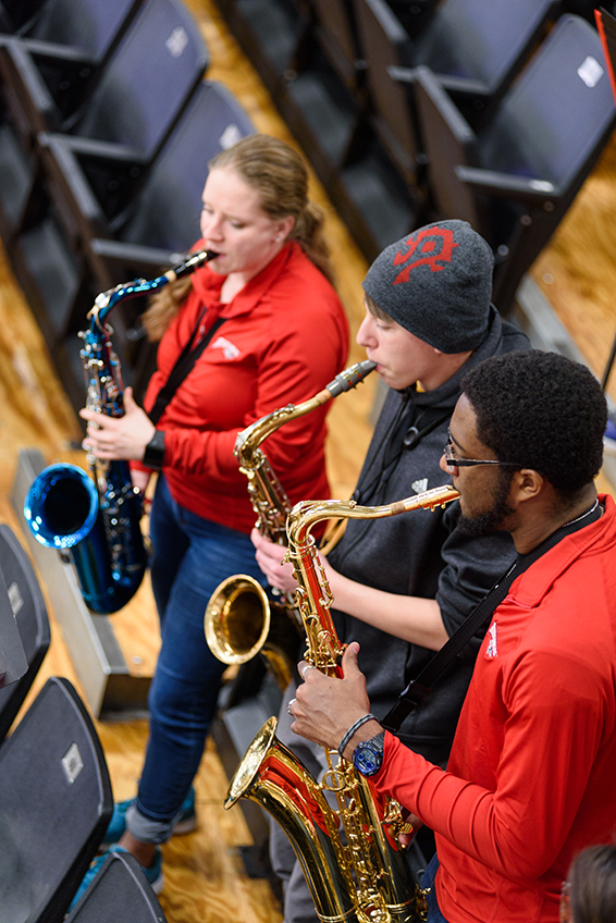 Three saxophonists playing at a basketball game