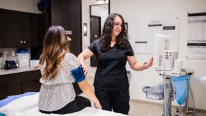 MSU Denver alumna Alejandra Webster, a recipient of the Deferred Action for Childhood Arrivals program seen here taking a person's blood pressure, became a registered nurse in 2021 and just started a new job at a private clinic. Photo by Alyson McClaran