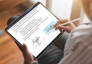 A person digitally signing a form on a tablet with a digital pen.