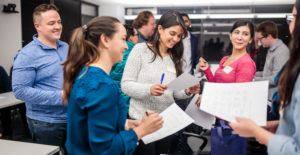 Adults are gathered in a group all while holding a piece of paper.