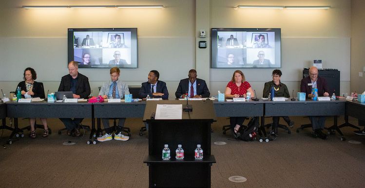 Eight members of the President's Cabinet sit on one side of a long rectangular table facing forward.