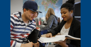 Two people discuss and point to a textbook.