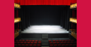 An empty stage with red seats.