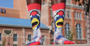 Close-up of a black man's feet wearing MSU Denver Rowdy branded socks in front of the Tivoli.
