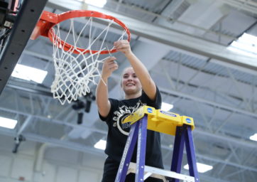 Women's basketball player Brianna Bailey cutting down the nets after MSU Denver's 2022 RMAC championship