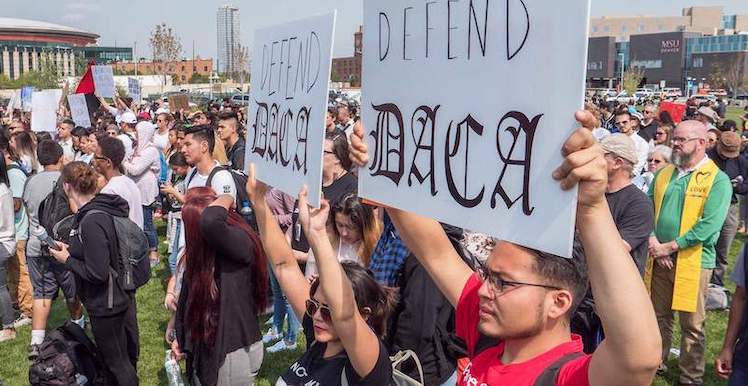 People gather on the Tivoli lawn with signs that say 