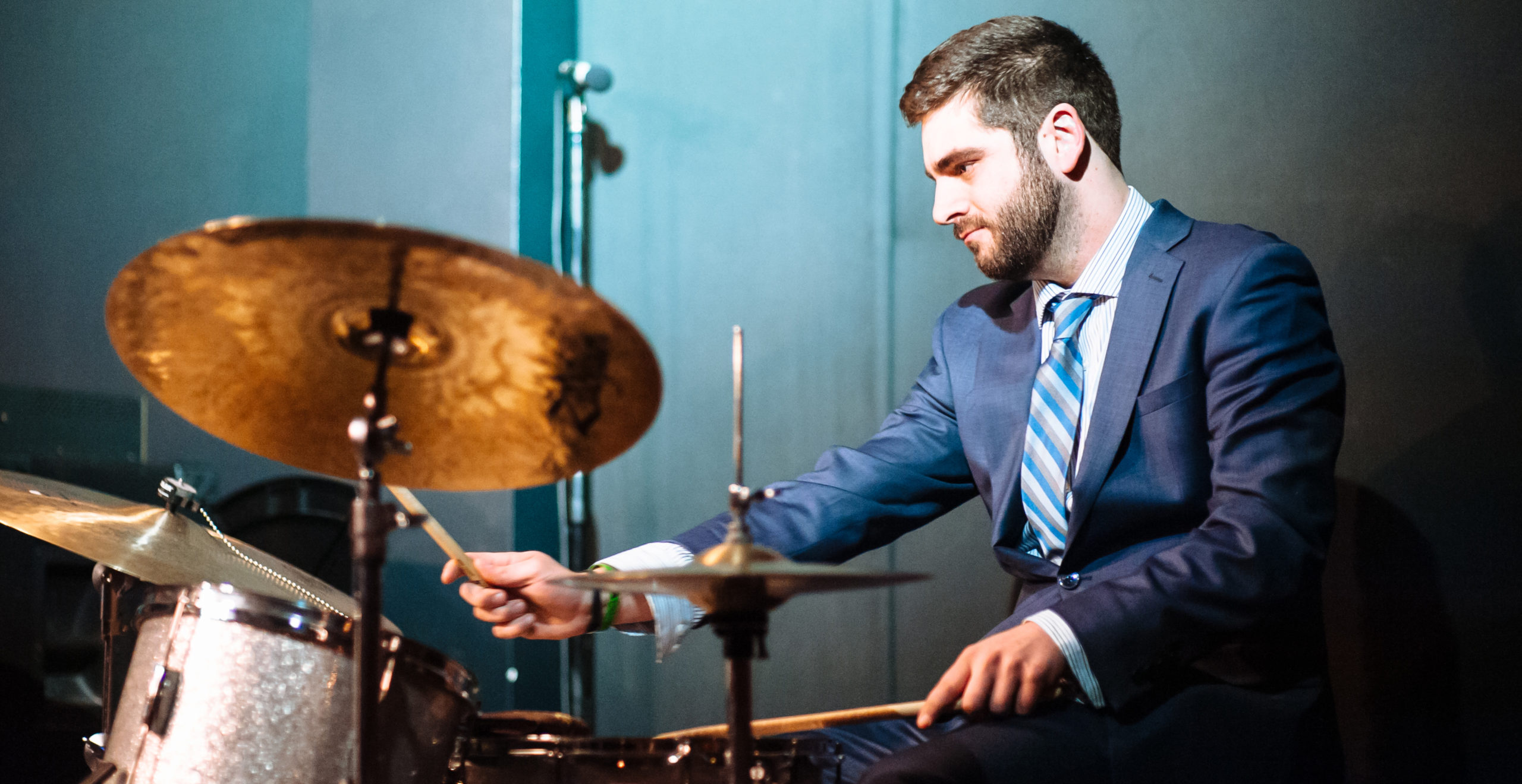 A drummer in a suit performing in a green room