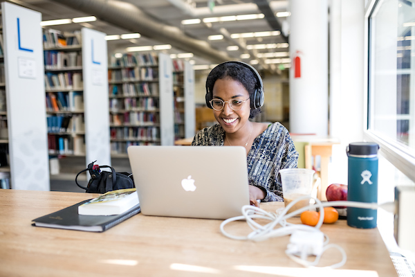 Smiling student working at her laptop in the library