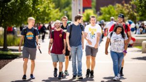 A group of 7 students laughing and walking on the Auraria campus