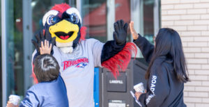 MSU Denver mascot, Rowdy giving high-fives to two students.