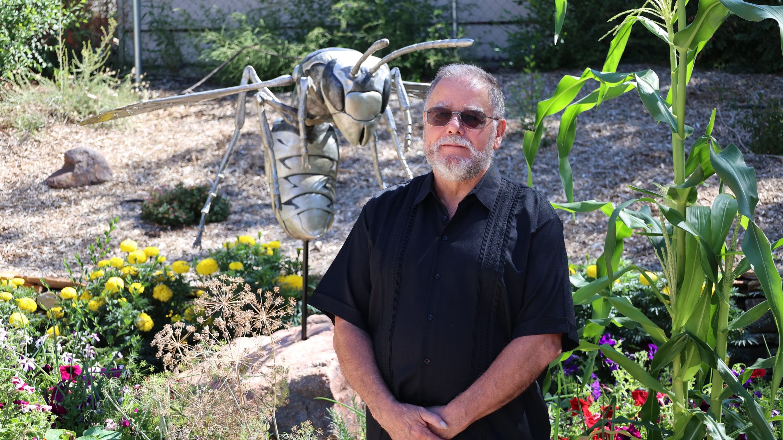 John Montaña standing in front of a piece of artwork, a metal sculpture of a wasp