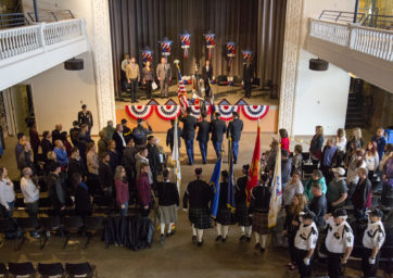 Military honor guards march with flags during the start of the Tri-Institutional Veterans Day ceremony on Auraria Campus, Denver, Colo. Nov. 11, 2017.