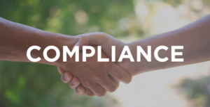 Two people shake hands with the word compliance over top.
