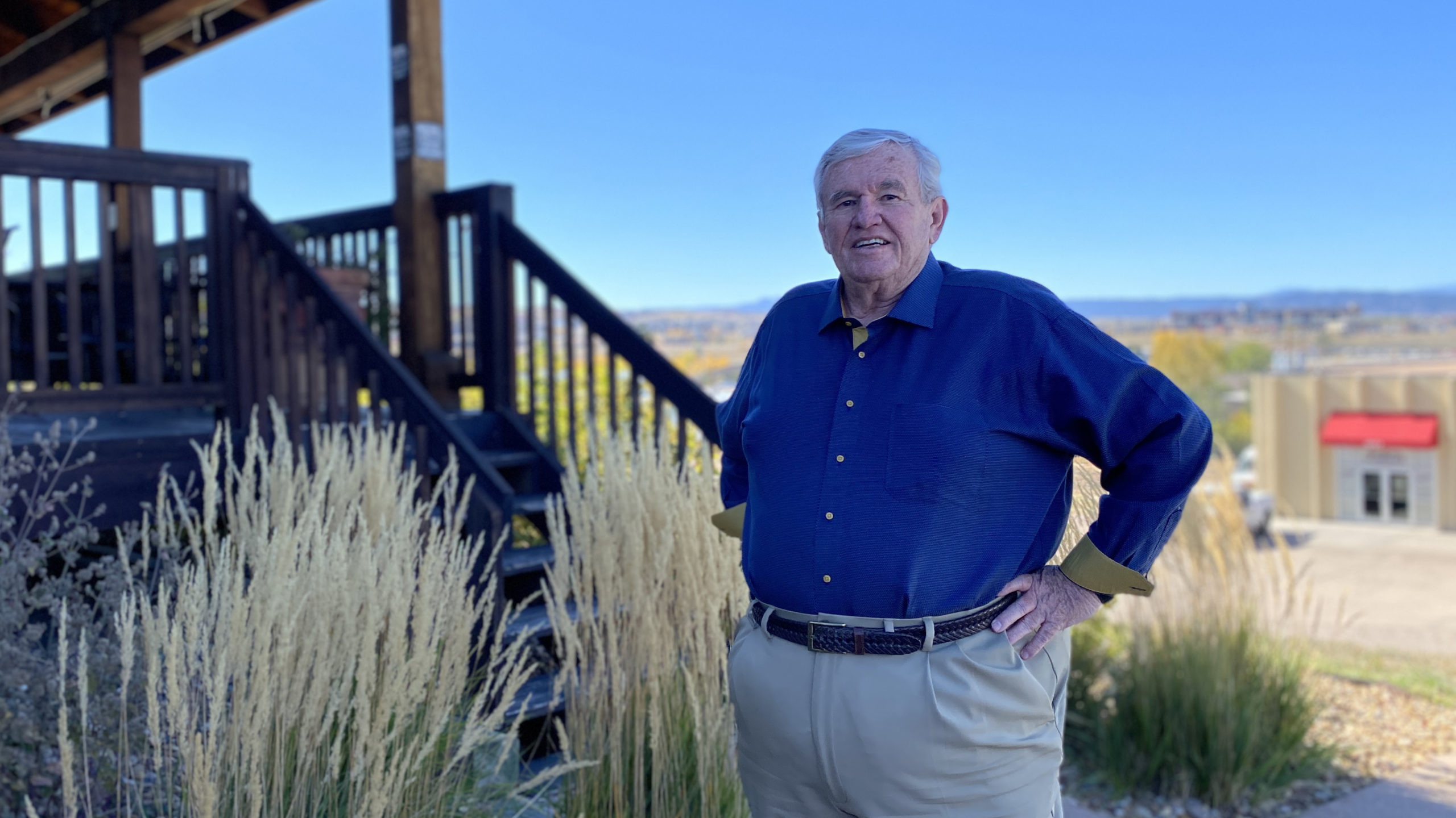 Jerry Hilderbrand standing at the bottom of stairs with mountains and fall colors in the background