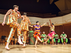 Dancers in traditional African dress performing in front of drummers