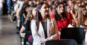 Close up of a person sitting in the front row with several filled rows behind them