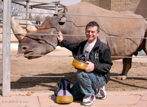 Student kneeling next to a rhinoceros