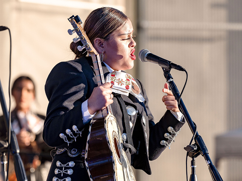 mariachi singer holding guitar and singing in microphone