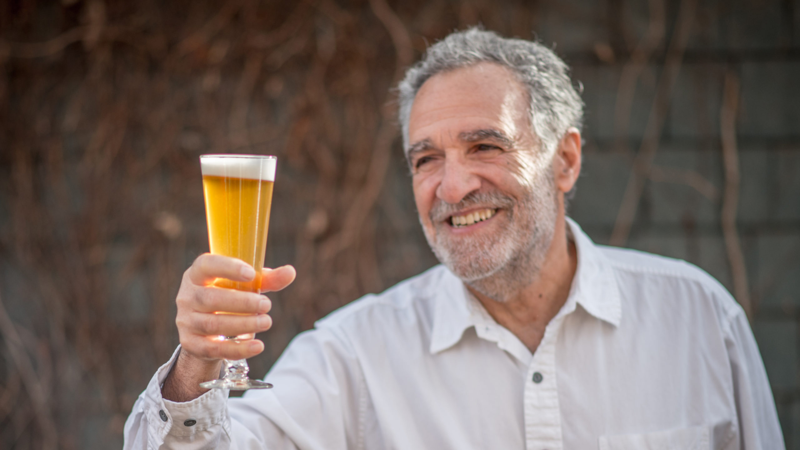 Charlie Papazian holding a beer glass
