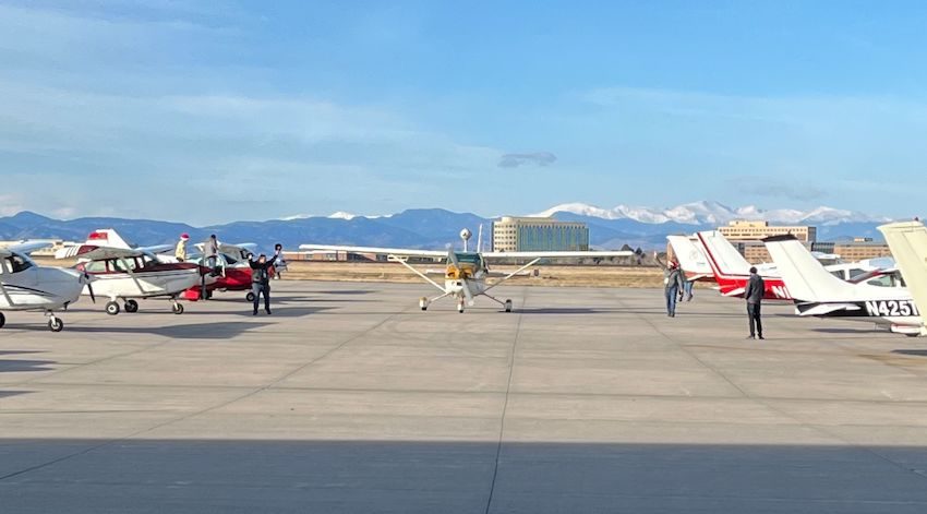 Frontal view of plane on the ground with mountains in the background.